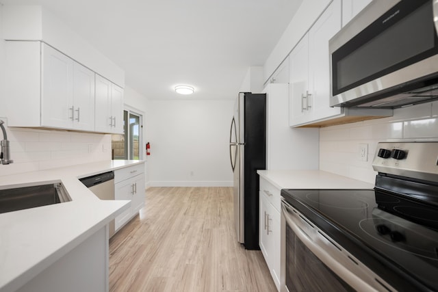 kitchen with white cabinets, stainless steel appliances, tasteful backsplash, and light hardwood / wood-style floors