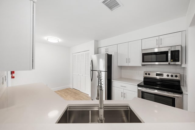 kitchen with white cabinets, sink, appliances with stainless steel finishes, and tasteful backsplash