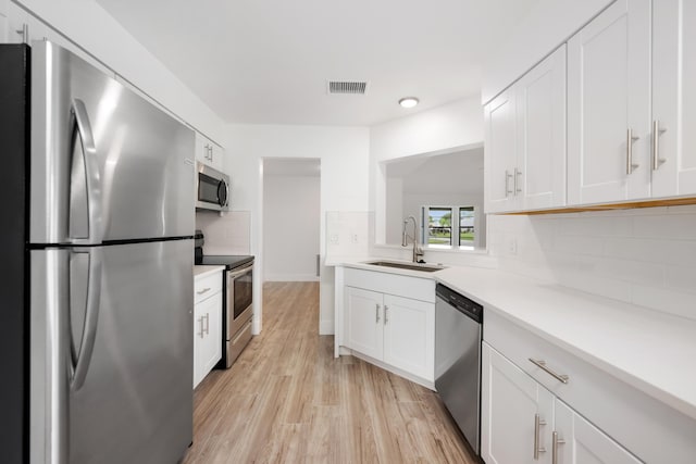 kitchen with white cabinets, backsplash, sink, and stainless steel appliances