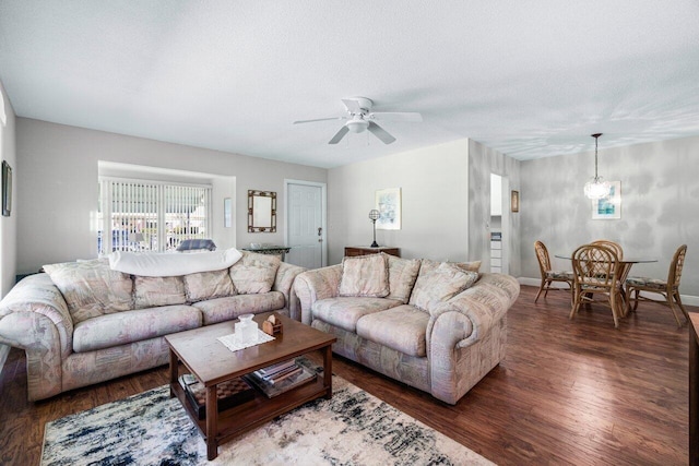 living room with a textured ceiling, ceiling fan, and dark wood-type flooring