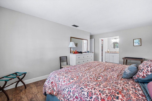 bedroom with ensuite bath and dark hardwood / wood-style floors