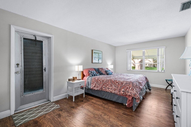 bedroom with a textured ceiling and dark hardwood / wood-style floors