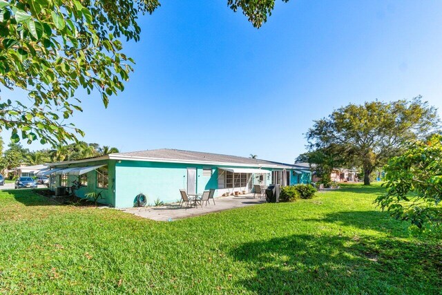 back of property featuring a lawn and a patio area