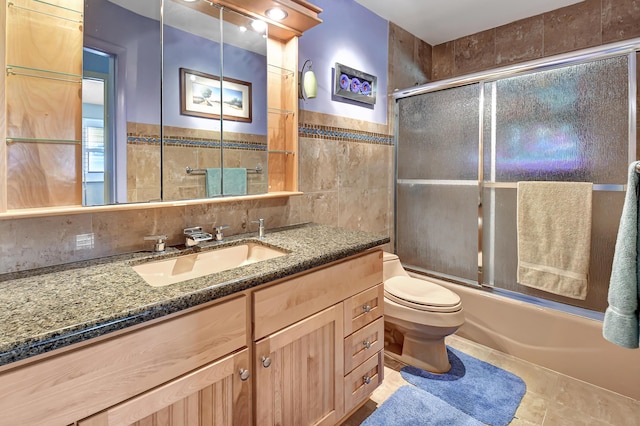 full bathroom with toilet, combined bath / shower with glass door, tile walls, vanity, and tile patterned flooring