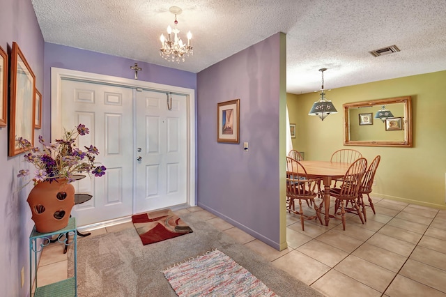 tiled foyer featuring a chandelier and a textured ceiling