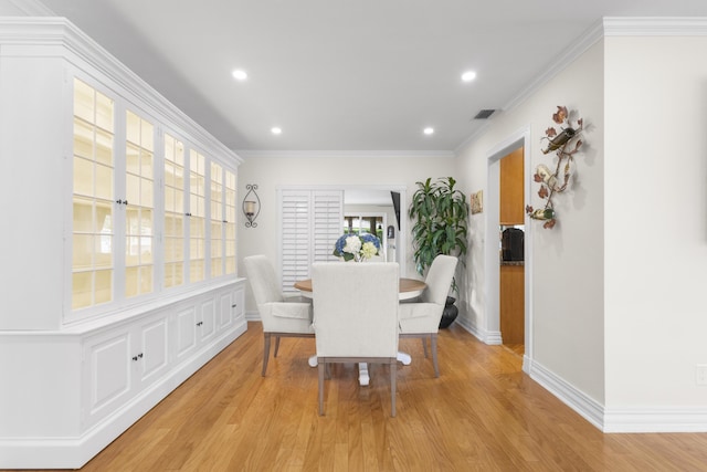 dining space featuring crown molding and light hardwood / wood-style floors