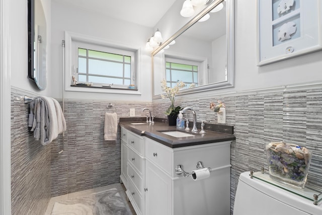 bathroom featuring vanity, toilet, and tile walls