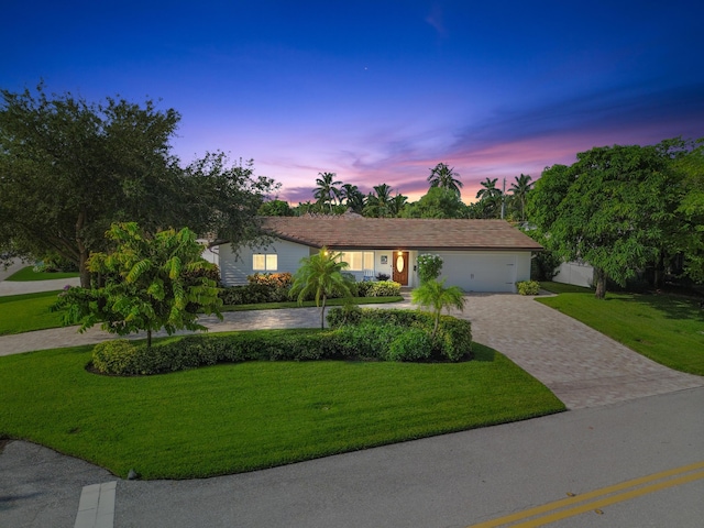 single story home featuring a lawn and a garage