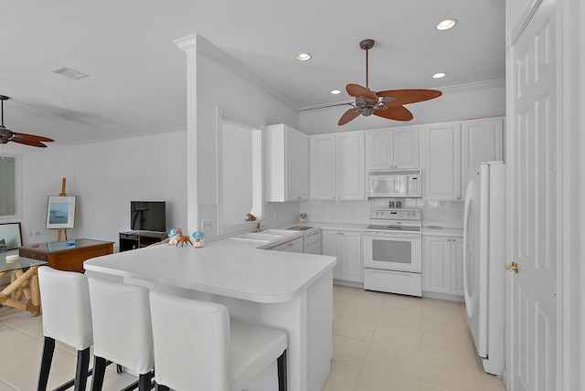 kitchen with white cabinetry, a kitchen breakfast bar, kitchen peninsula, white appliances, and decorative backsplash