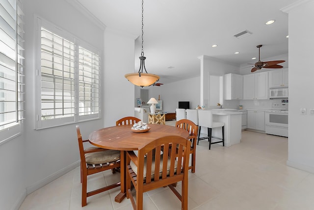 tiled dining space featuring ceiling fan and ornamental molding