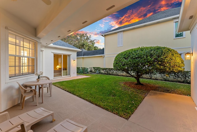 yard at dusk featuring a patio