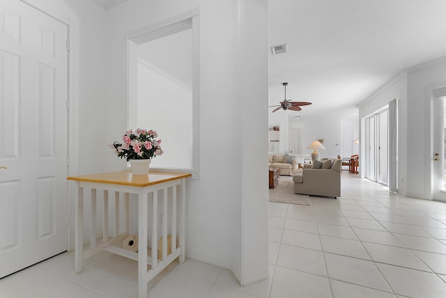 hallway with light tile patterned floors and crown molding