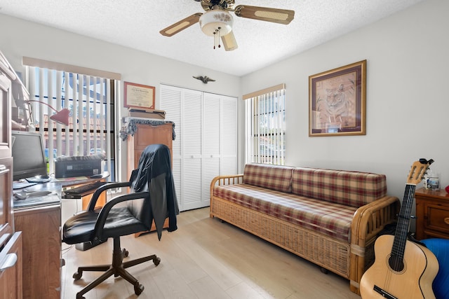 office featuring a textured ceiling, light hardwood / wood-style flooring, plenty of natural light, and ceiling fan