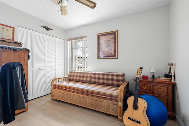 sitting room featuring ceiling fan, a textured ceiling, and light wood-type flooring