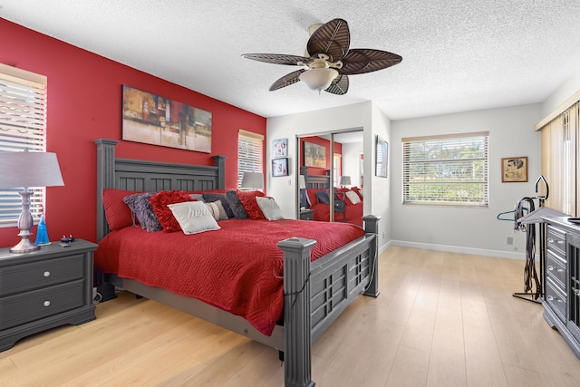 bedroom with a textured ceiling, light wood-type flooring, and ceiling fan