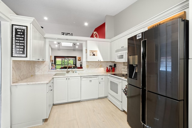 kitchen featuring backsplash, white appliances, sink, white cabinets, and lofted ceiling