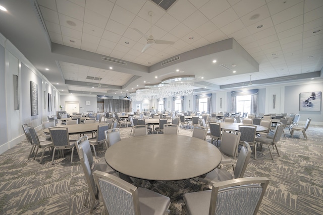 carpeted dining room with a raised ceiling and ceiling fan