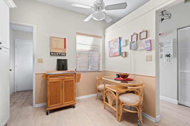 dining room featuring light wood-type flooring, a textured ceiling, and ceiling fan