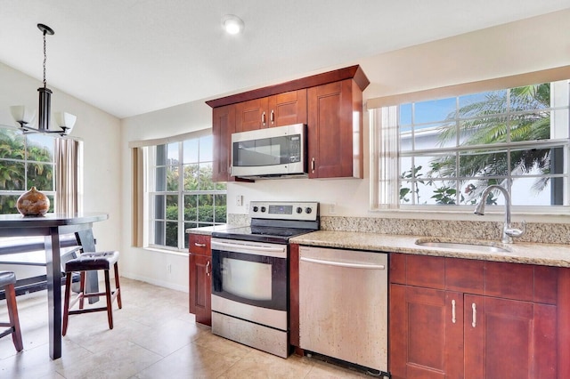 kitchen featuring sink, stainless steel appliances, a chandelier, vaulted ceiling, and decorative light fixtures