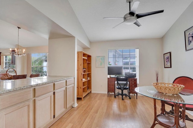 office featuring ceiling fan with notable chandelier, light wood-type flooring, a wealth of natural light, and lofted ceiling