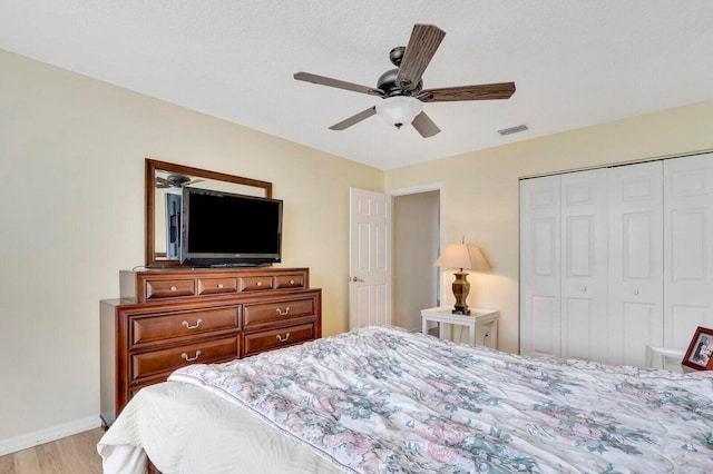 bedroom with a closet, light hardwood / wood-style flooring, and ceiling fan