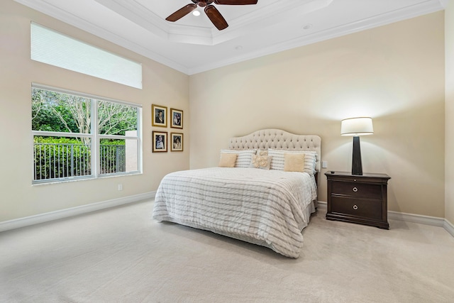 carpeted bedroom with ceiling fan, a tray ceiling, and ornamental molding