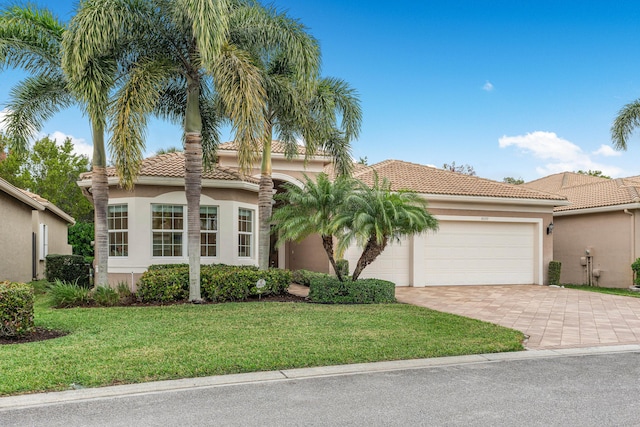 mediterranean / spanish home featuring a front yard and a garage