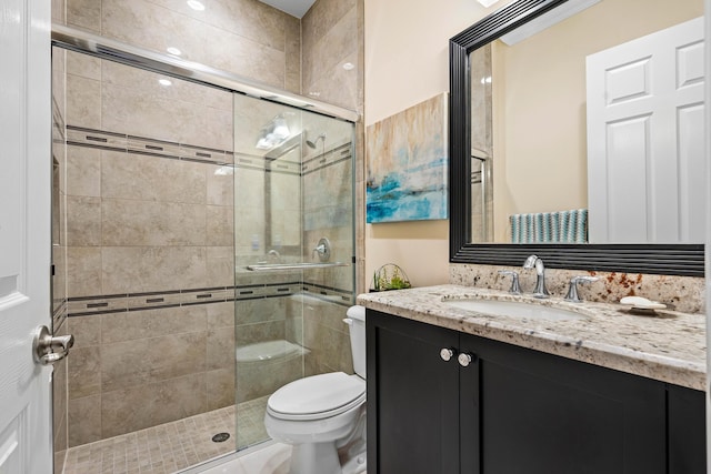 bathroom featuring toilet, vanity, and an enclosed shower