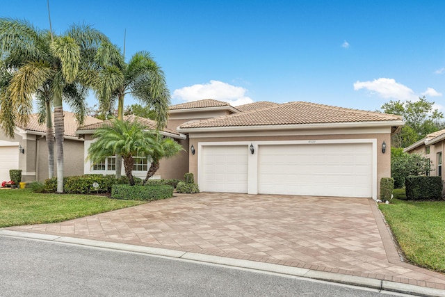 mediterranean / spanish home with a garage and a front lawn