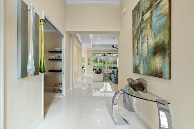 corridor with ornamental molding and a raised ceiling