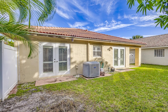 rear view of house featuring a lawn, cooling unit, and french doors