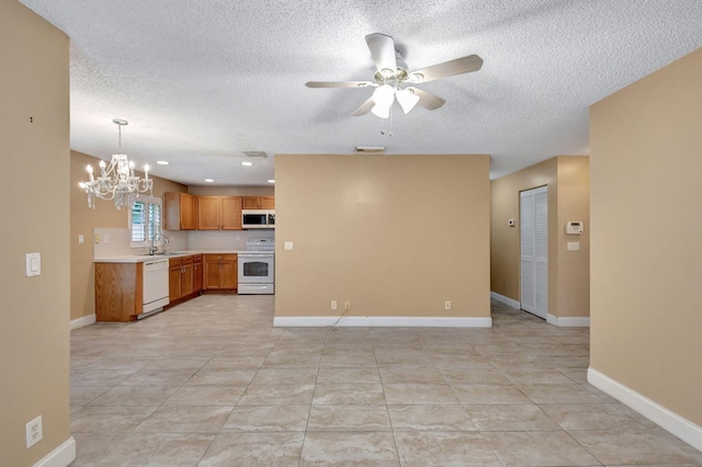 kitchen with ceiling fan with notable chandelier, white appliances, sink, hanging light fixtures, and light tile patterned floors