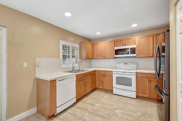 kitchen featuring sink, white appliances, and a textured ceiling