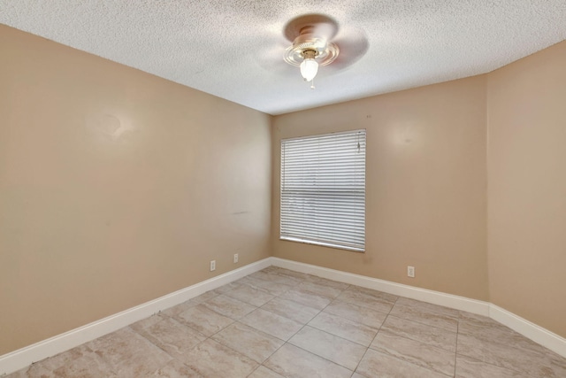 empty room with ceiling fan, light tile patterned floors, and a textured ceiling