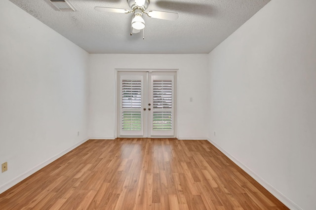 spare room featuring ceiling fan, a textured ceiling, light hardwood / wood-style flooring, and french doors