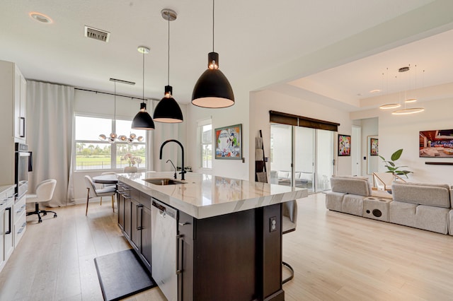 kitchen featuring sink, an island with sink, pendant lighting, and stainless steel dishwasher