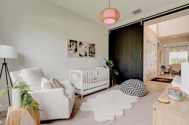 bedroom featuring a barn door, hardwood / wood-style floors, and a nursery area