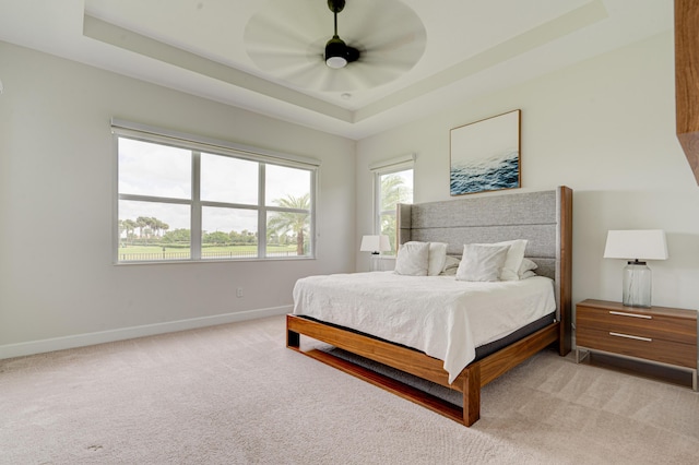 carpeted bedroom with ceiling fan and a tray ceiling