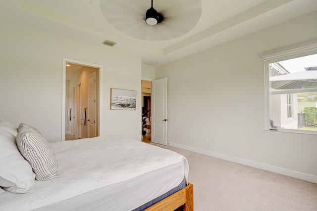 carpeted bedroom with a raised ceiling and ceiling fan