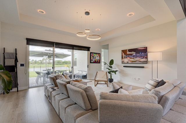 living room with light hardwood / wood-style flooring and a tray ceiling