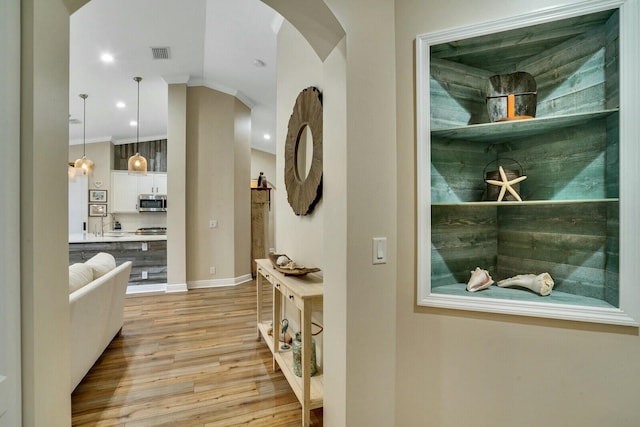 hallway with light wood-type flooring, crown molding, and sink