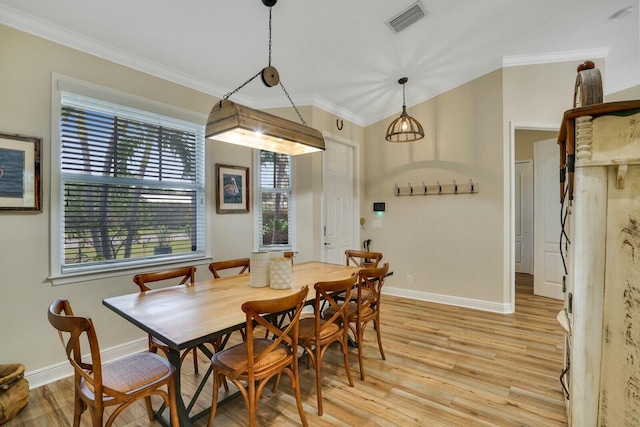 dining space with ornamental molding and light hardwood / wood-style floors