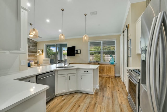 kitchen with kitchen peninsula, sink, white cabinetry, hanging light fixtures, and appliances with stainless steel finishes