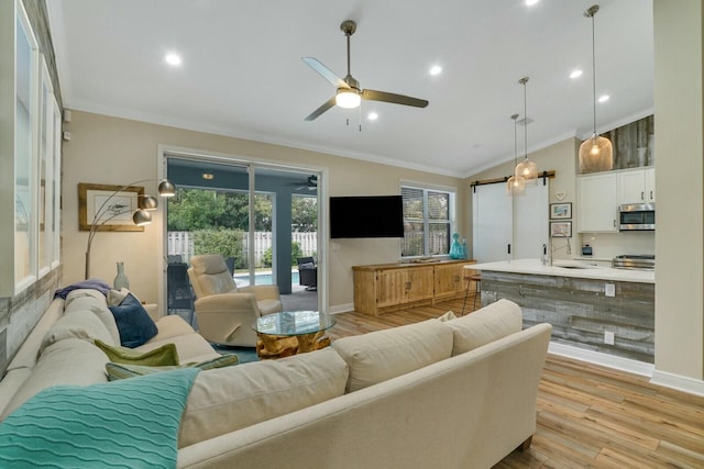 living room featuring ceiling fan, ornamental molding, light hardwood / wood-style flooring, and sink