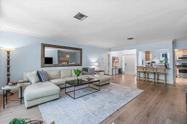 living room featuring light hardwood / wood-style floors, ornamental molding, and sink