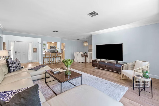 living room with crown molding and light hardwood / wood-style floors