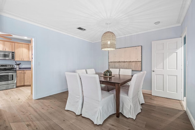 dining room featuring light hardwood / wood-style floors and crown molding