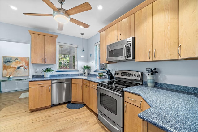 kitchen featuring sink, ceiling fan, appliances with stainless steel finishes, decorative light fixtures, and light hardwood / wood-style floors