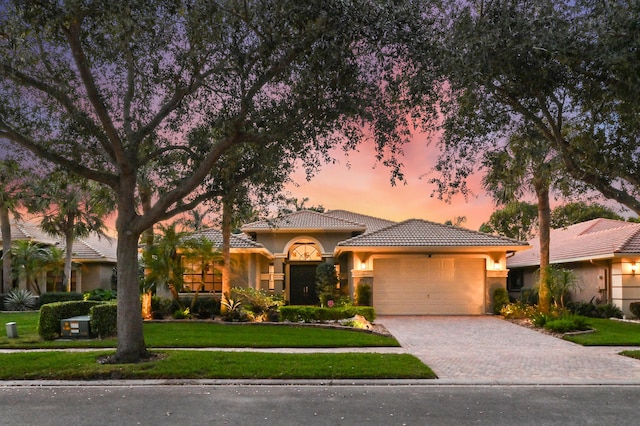 mediterranean / spanish-style house with a lawn and a garage