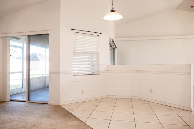 spare room featuring tile patterned flooring, a healthy amount of sunlight, and lofted ceiling